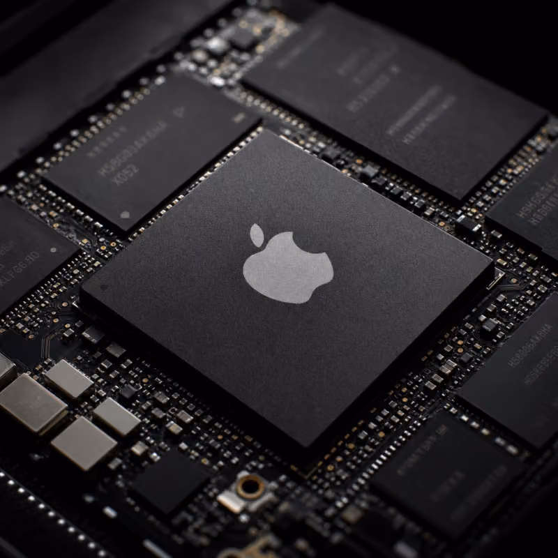 Macro shot of an Apple chip with Apple logo on a motherboard, surrounded by memory modules.